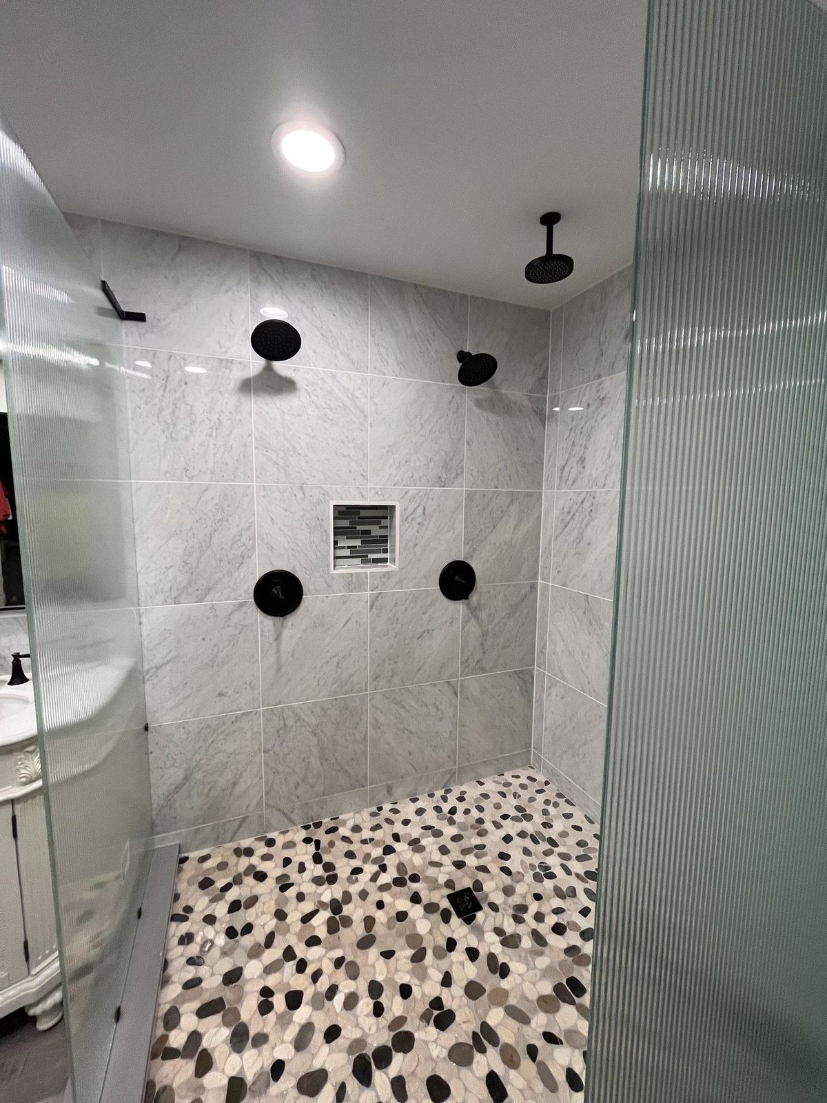 Hewitt bathroom after — custom shower with marble-look tile and pebble floor