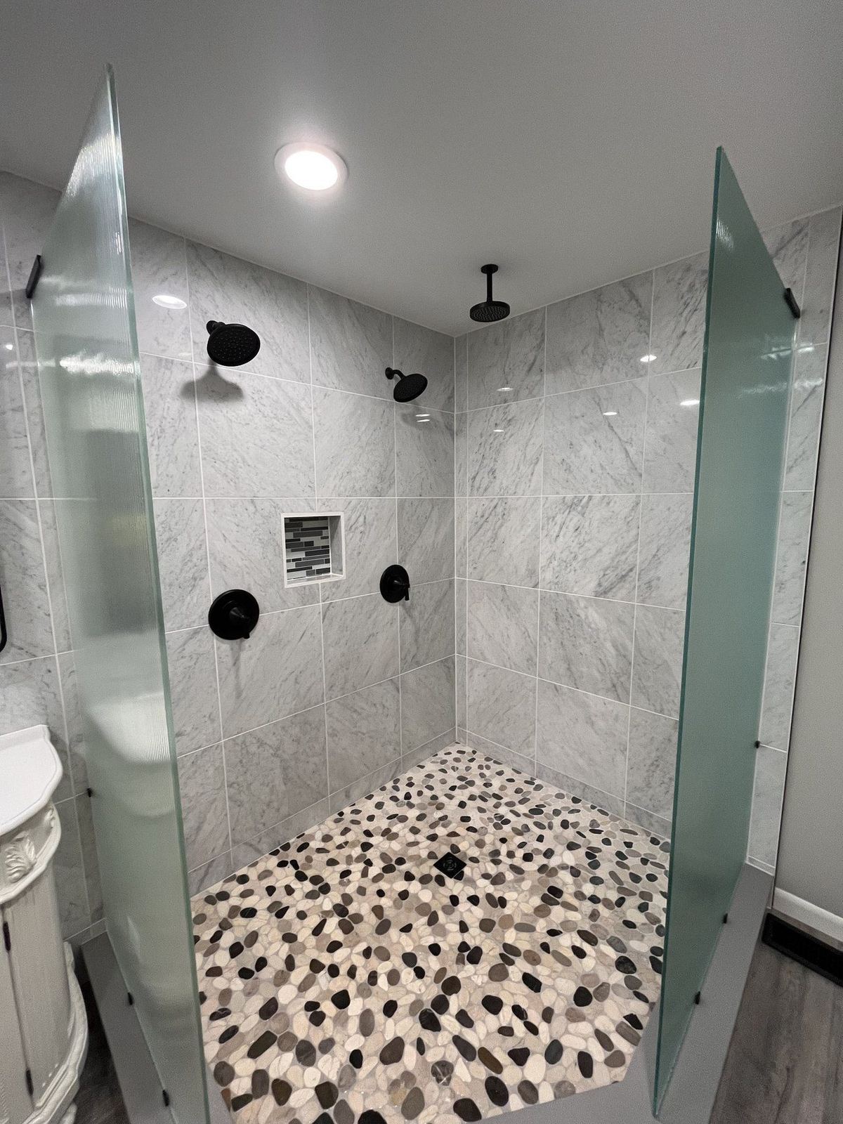 Custom shower with marble tile walls and pebble floor