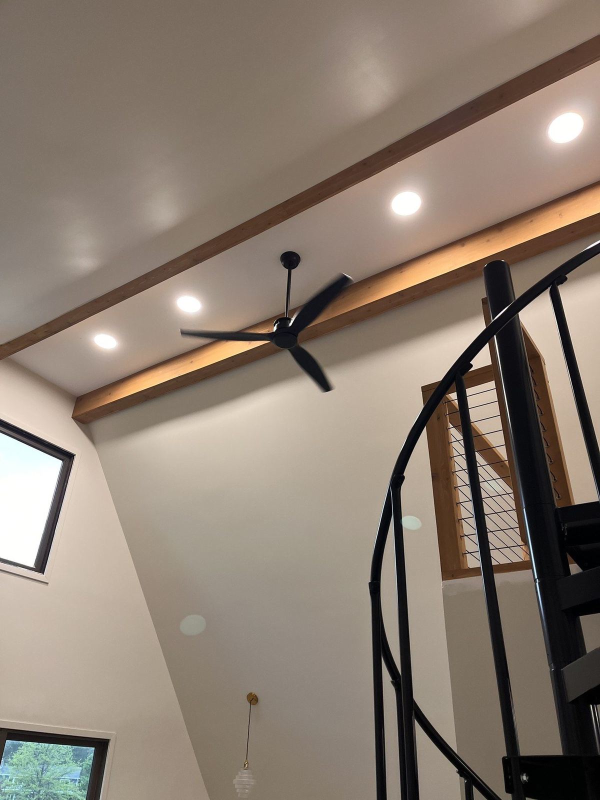 Vaulted ceiling with exposed wood beams and spiral staircase after renovation